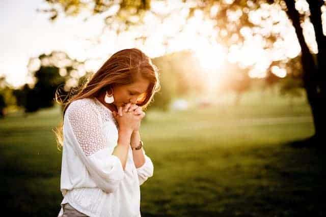 woman with head down praying outside