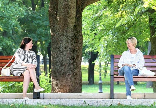 Feeling like you are not enough? two women sitting on park benches.