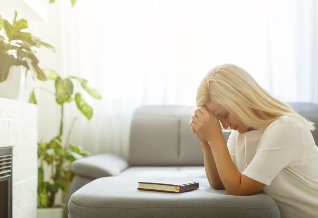 woman on her knees praying over her Bible