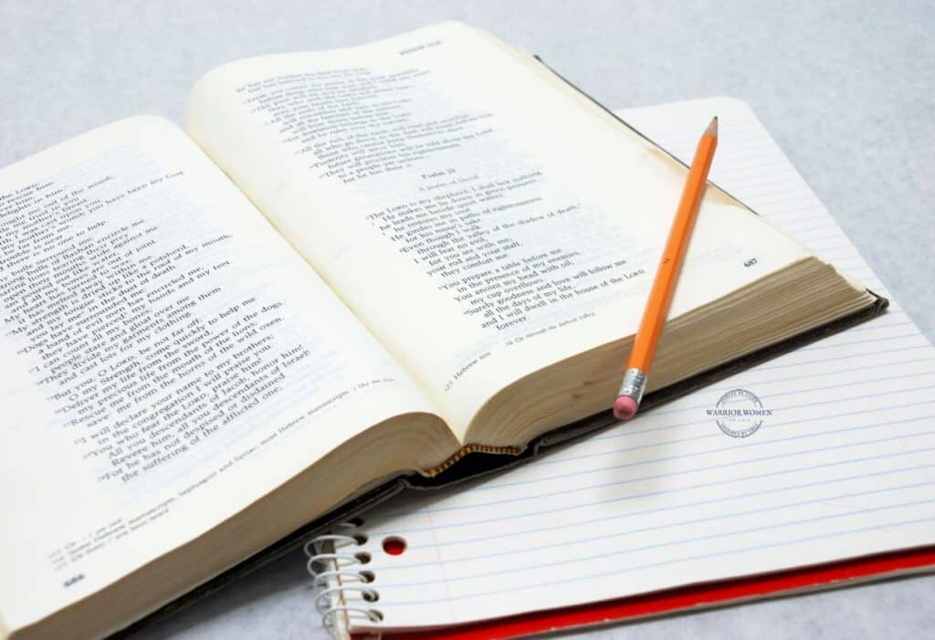 open Bible with pencil across it and notebook underneath