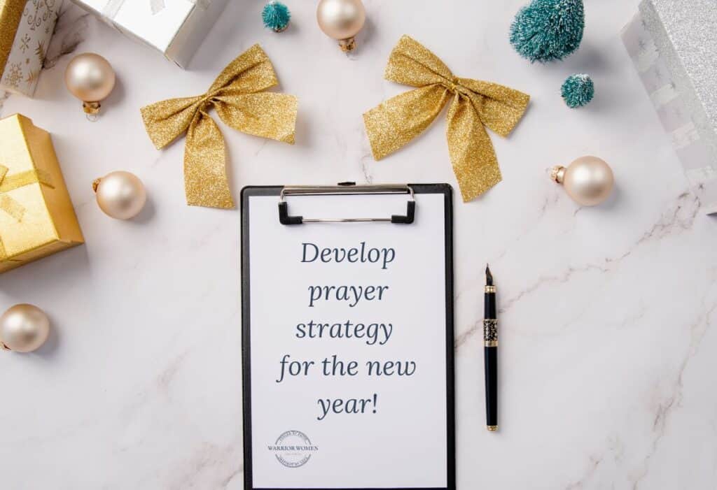 table with gold bows, a clipboard with "Develop prayer strategy for the new year" written on it with a pen beside it