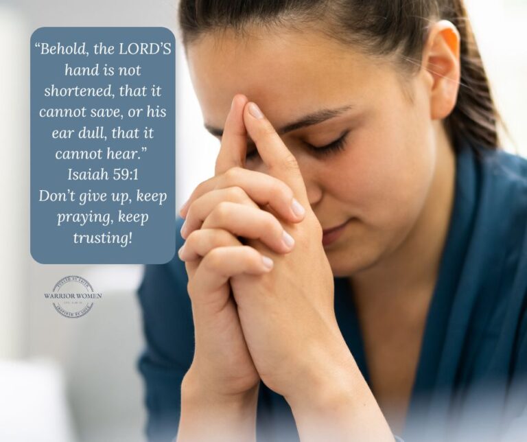 woman in blue shirt with head bowed in prayer and hands near her face