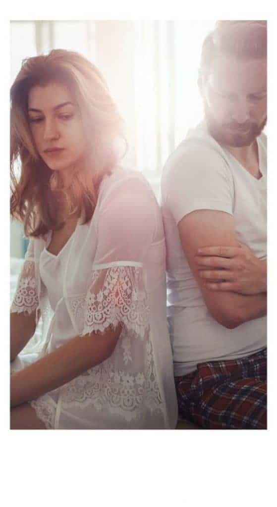 man and woman sitting on bed with backs to each other